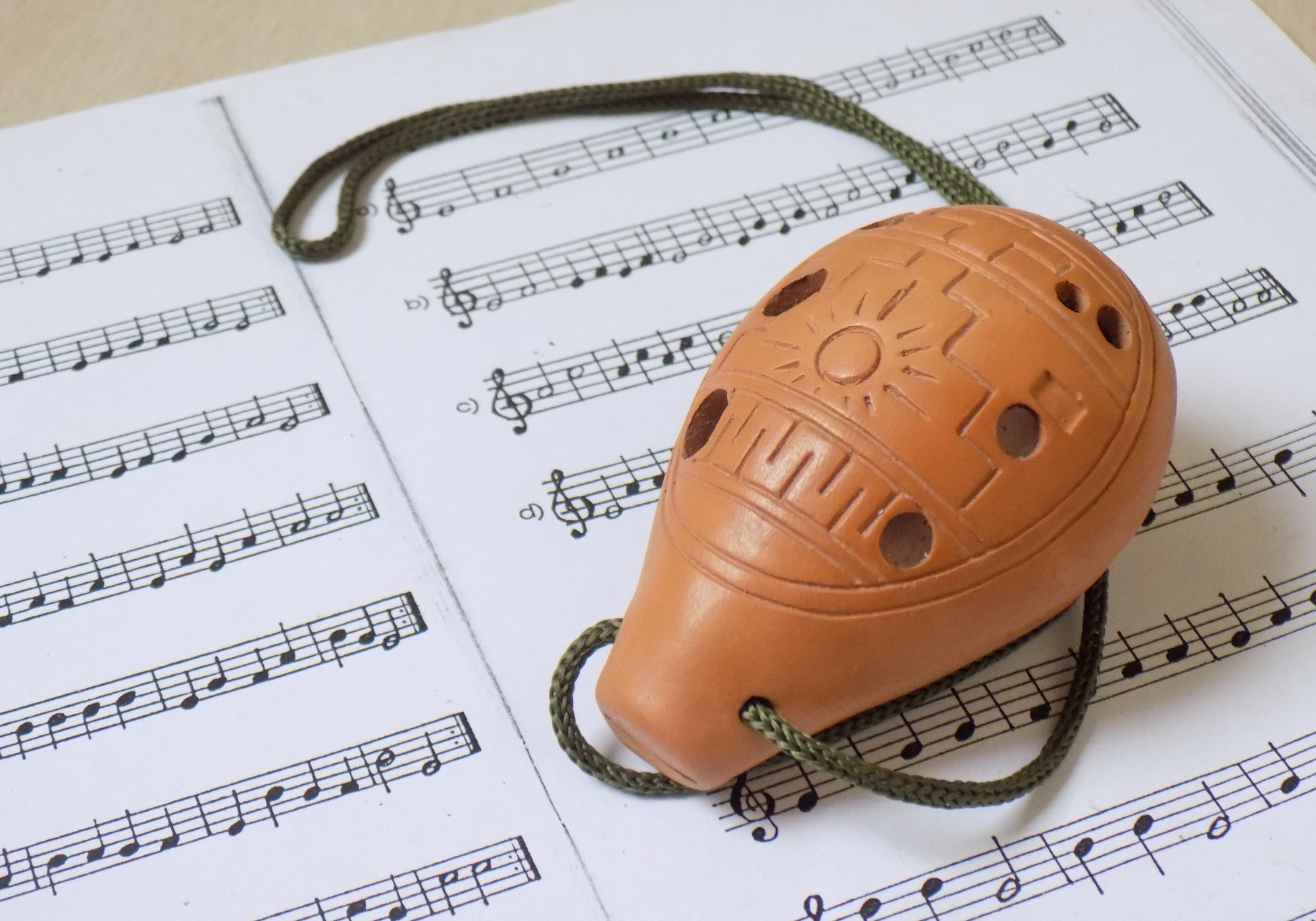 Uma Ocarina de 9 furos em cima de uma partitura impressa